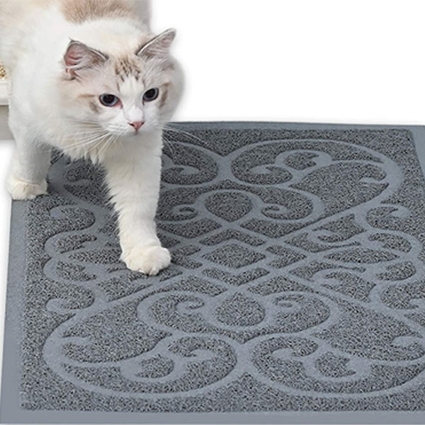 a white kitty is walking on grey cat litter mat